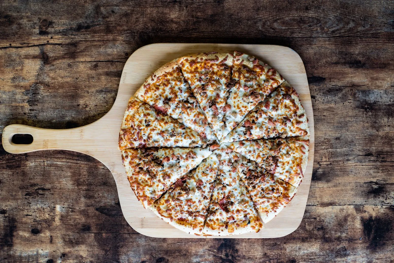 Top view of a cheesy pizza on a wooden board, perfect for food photography.
